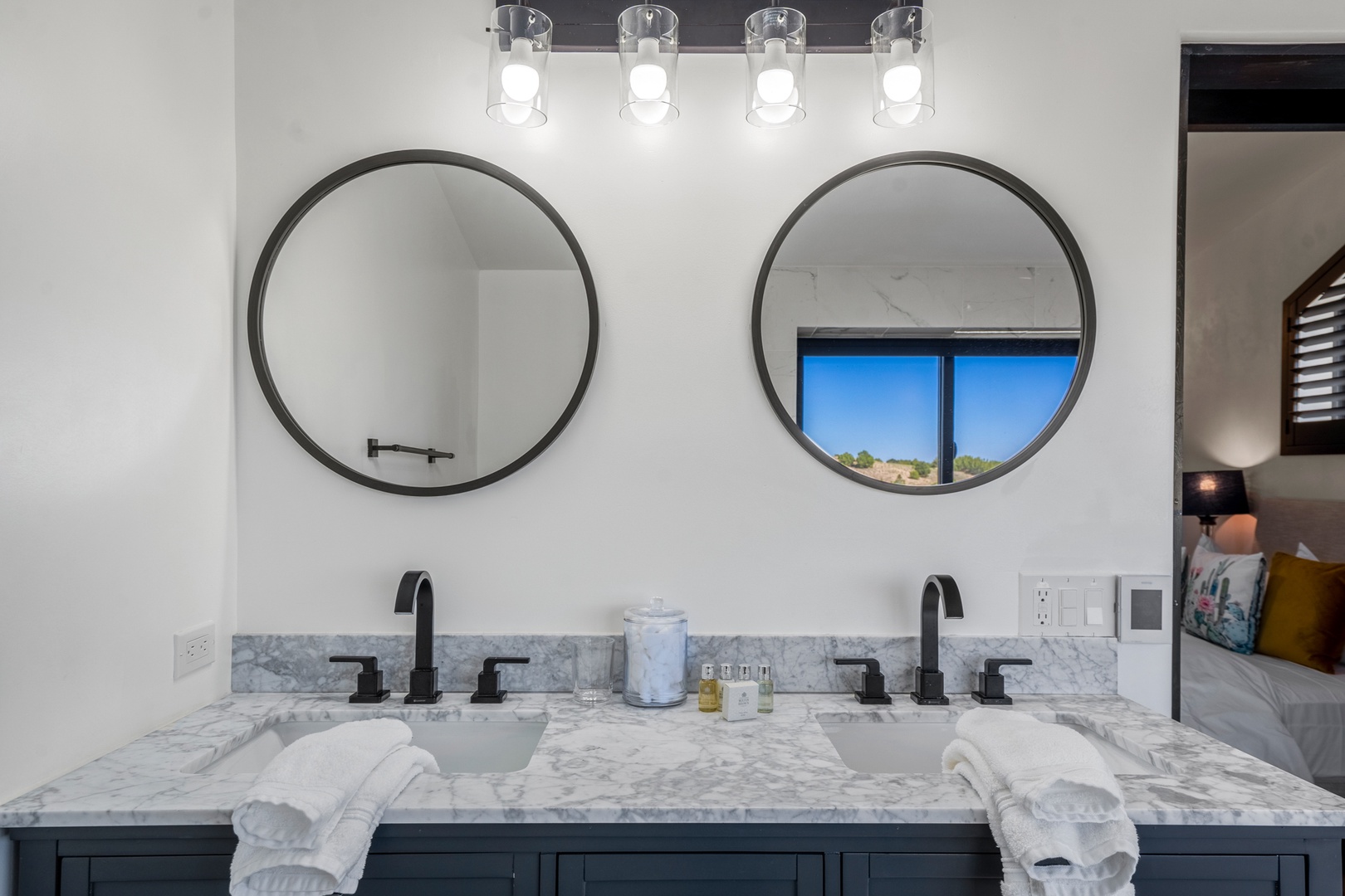 Your luxurious double vanity bathroom features elegant marble countertops, modern round mirrors, and thoughtful amenities for a spa-like morning routine.
