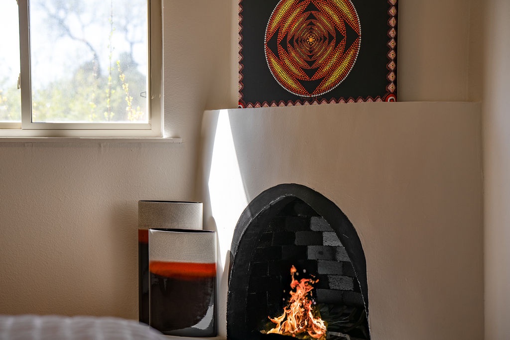 Cozy up beside your crackling fireplace, where vibrant artwork and warm flames create the perfect atmosphere for relaxation.