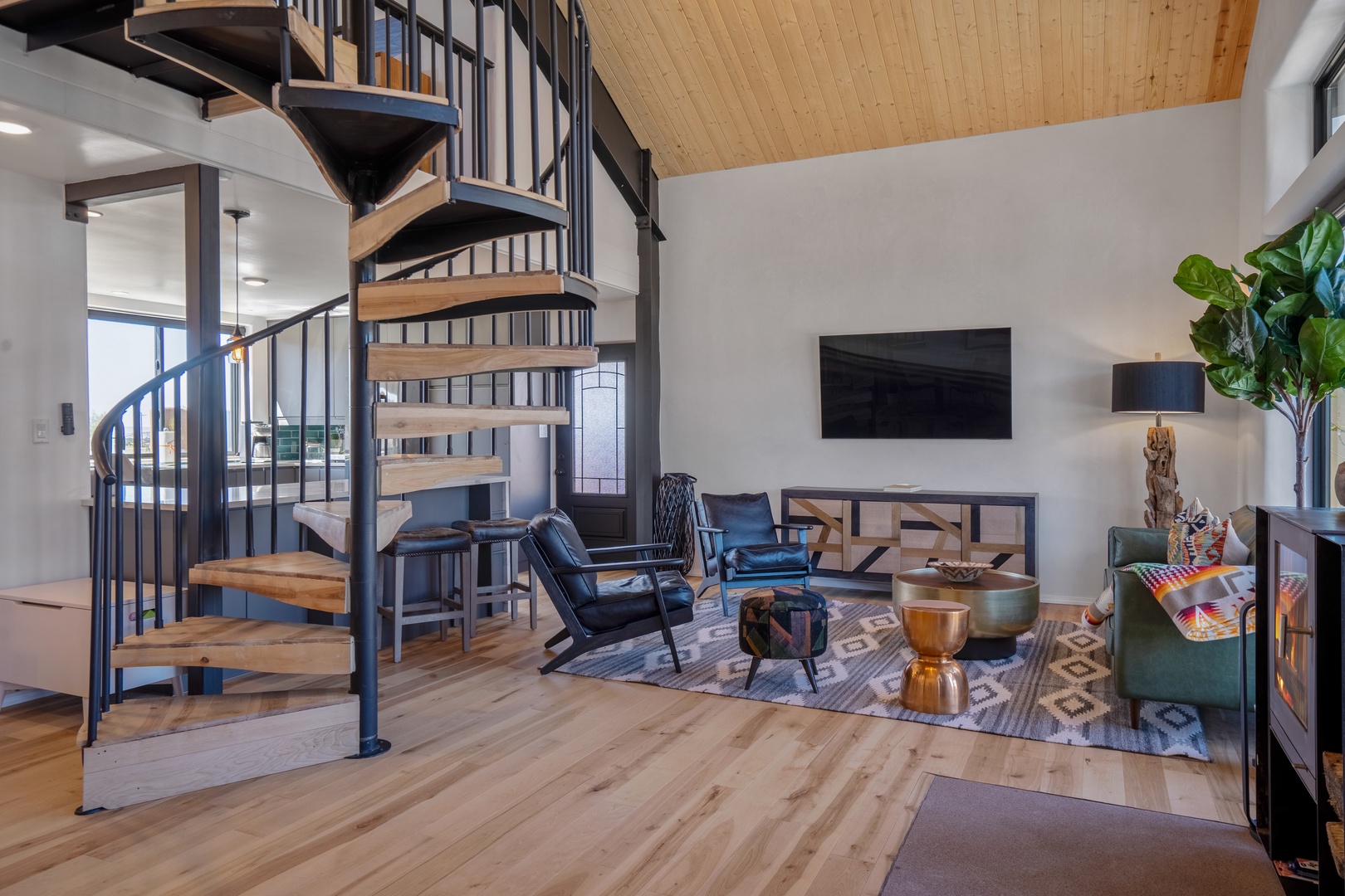 Relax in your stylish living room with modern furniture, warm wood accents, and a stunning spiral staircase creating an open, airy atmosphere.