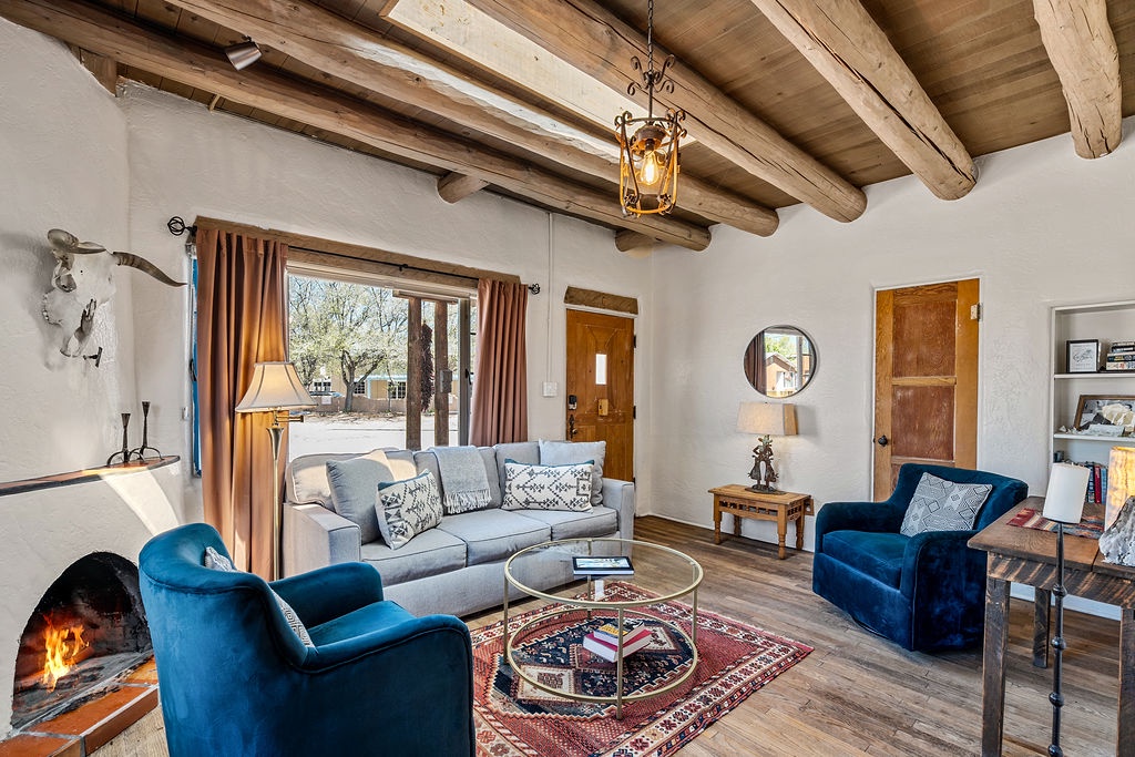 Unwind in your charming living room where rustic wooden beams meet cozy blue armchairs by a crackling fireplace.