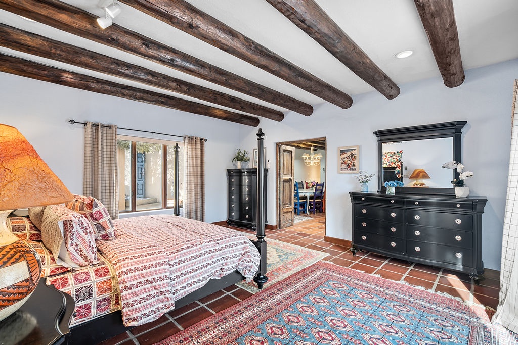 Rest beneath rustic exposed beams in your charming bedroom, where traditional Spanish tiles meet elegant furnishings for ultimate comfort.