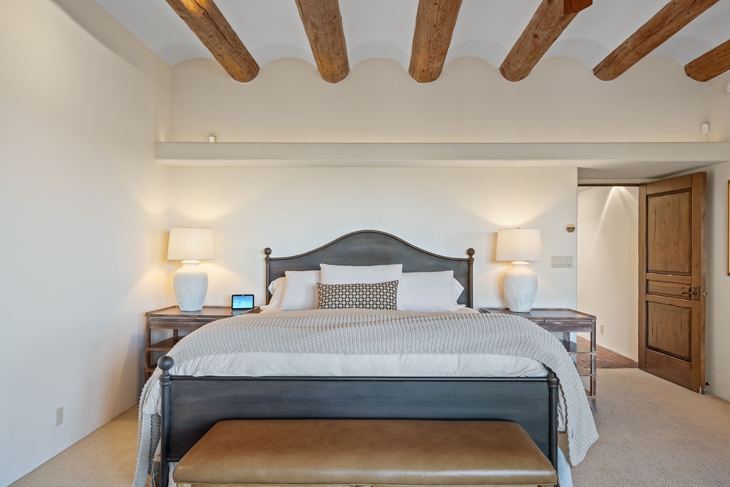 Drift off under rustic wooden beams in your serene bedroom, where crisp linens and warm lighting create the perfect retreat.