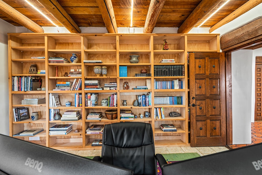 Settle into your private study sanctuary, where floor-to-ceiling wooden shelves invite you to discover literary treasures beneath stunning exposed beam ceilings.