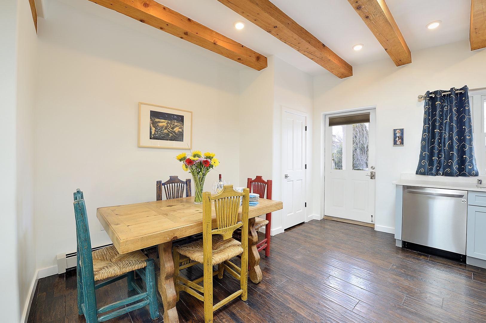Gather around this charming farmhouse dining table under rustic beams. Your conversations will flow naturally in this warm space.