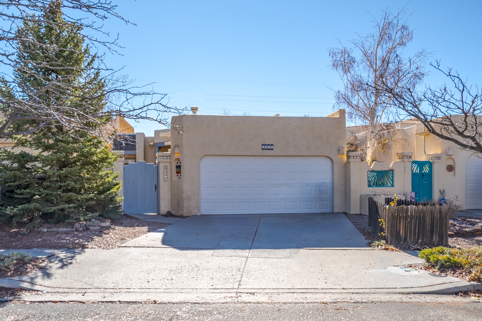 Southwestern-style property with distinctive turquoise accents and private garage, located in a quiet residential neighborhood.