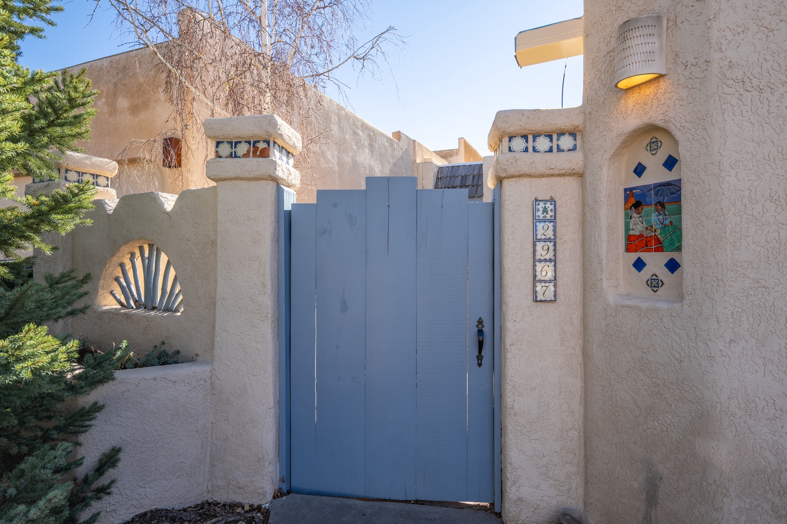 Distinctive blue entrance gate with decorative address tiles and southwestern architectural details mark your arrival at this unique adobe-style property.