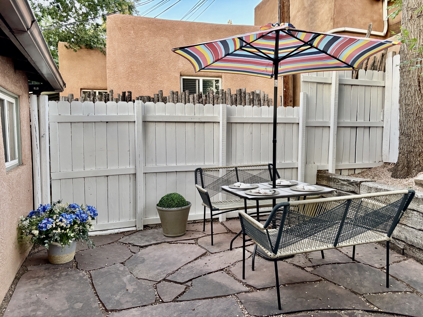 Relax in your private patio oasis with comfortable seating, cheerful umbrella shade, and lovely garden touches for peaceful outdoor dining.