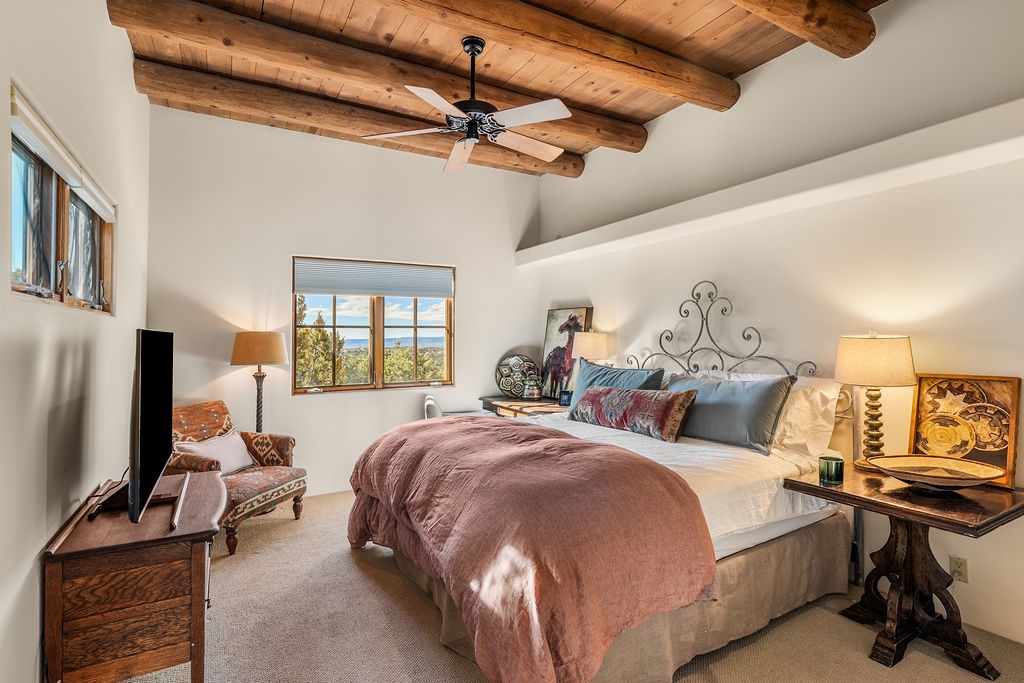 Drift off beneath rustic wooden beams in your serene bedroom, where warm textures and mountain views create the perfect retreat.