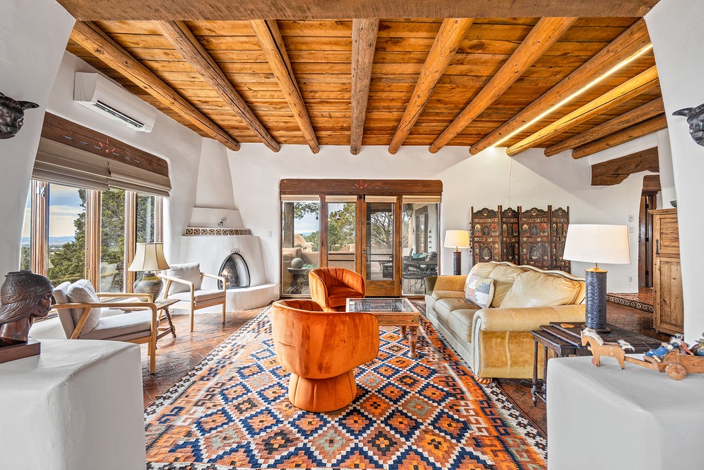 Relax in your spacious living room with exposed wooden beams, cozy fireplace, and vibrant southwestern décor overlooking scenic mountain views.