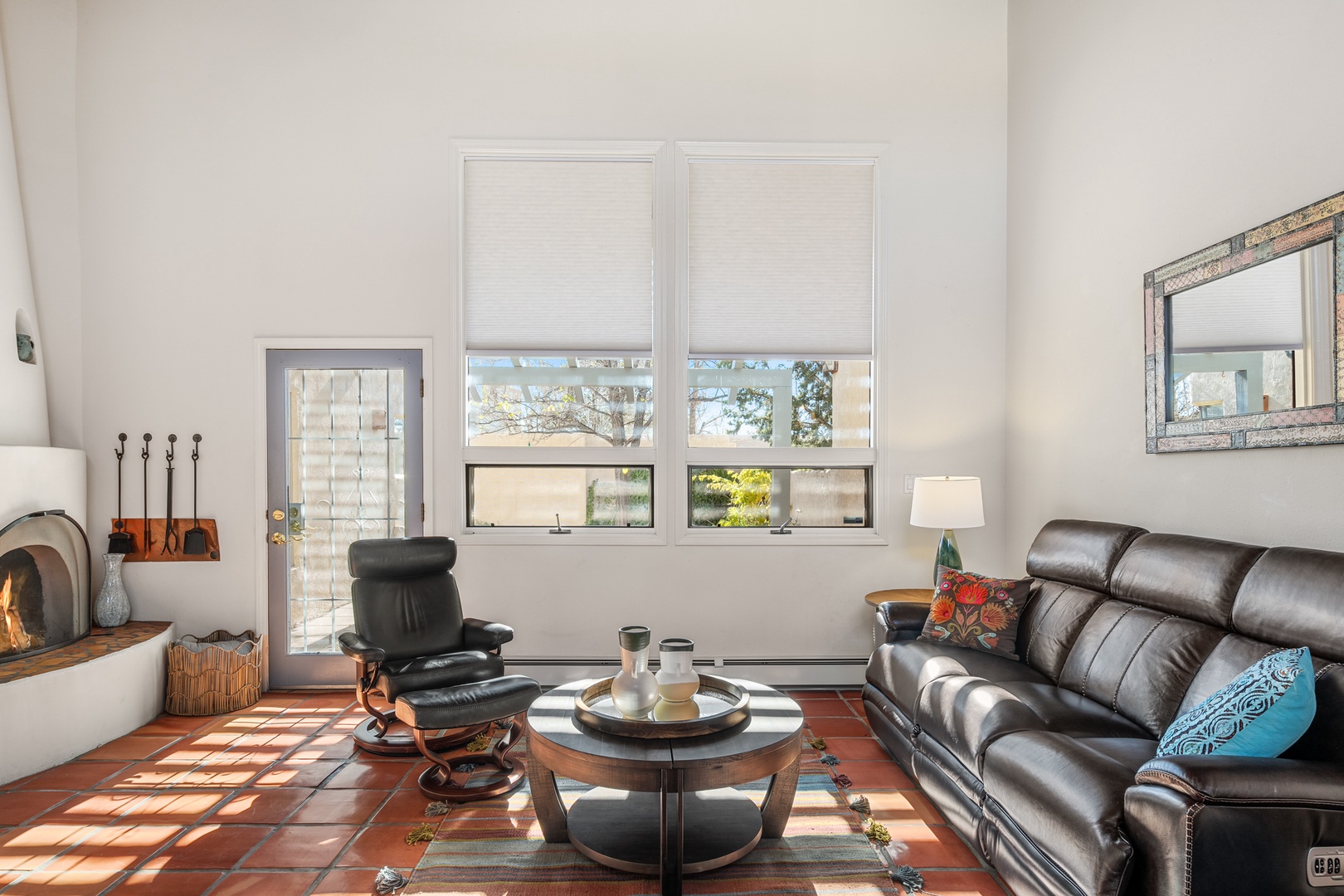 Relax in your comfortable living room with leather seating, cozy fireplace, and natural light streaming through large windows.