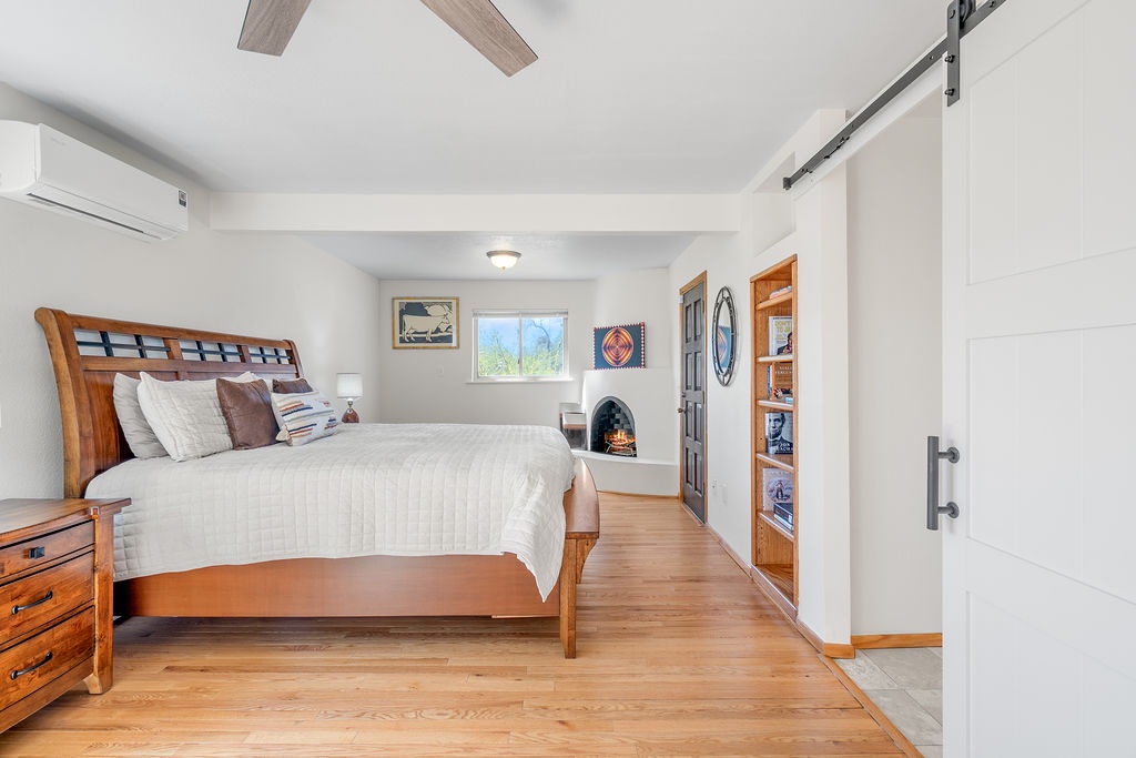 Relax in your cozy bedroom featuring warm wood floors, a charming fireplace, and thoughtful touches that create the perfect retreat.