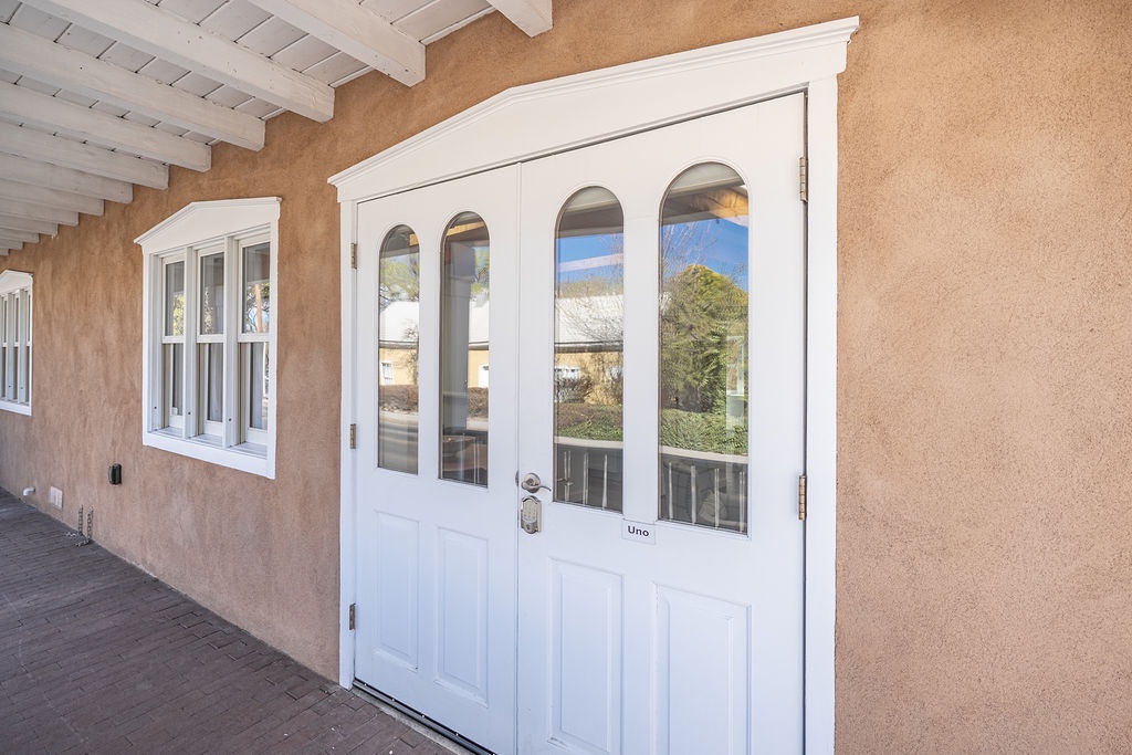 Charming adobe-style entrance with white exposed beams and traditional Southwestern architecture welcomes guests to this desert retreat.