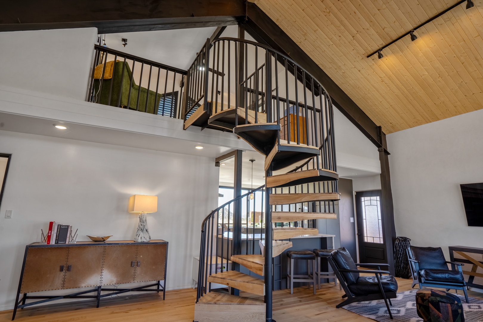 Your stylish retreat features a stunning spiral staircase and open living space with warm wood accents and leather seating.