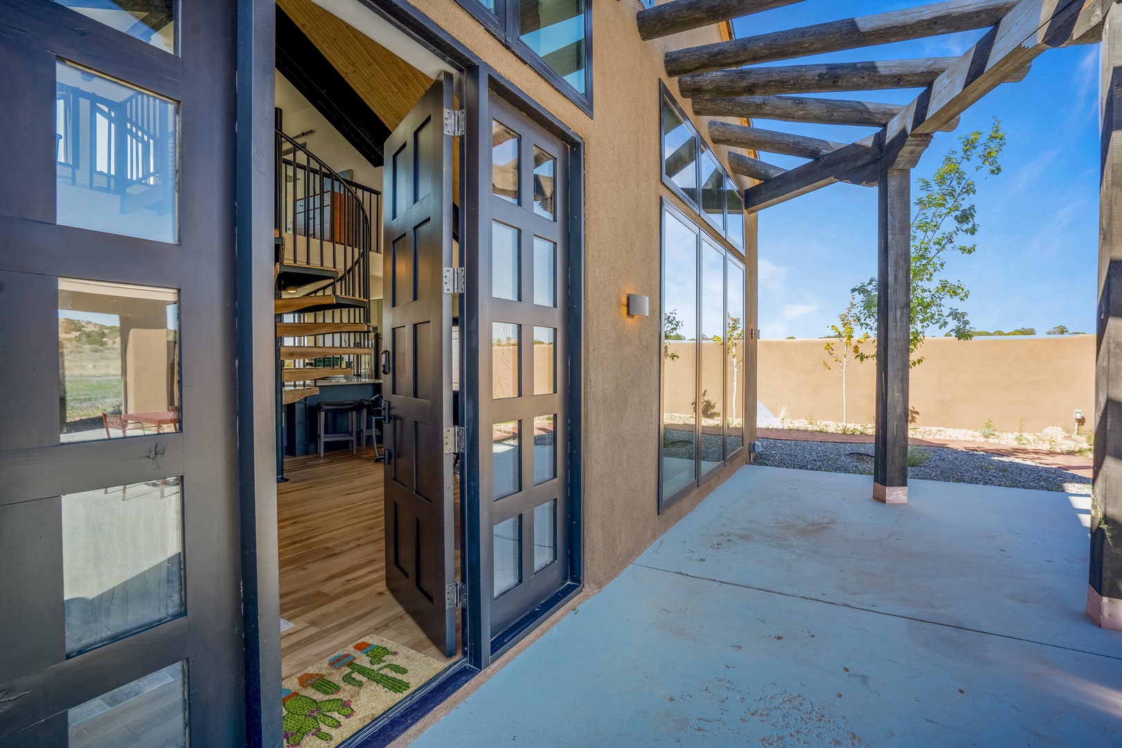 Step into your private covered patio with wooden pergola beams and glass doors opening to reveal stylish interiors.