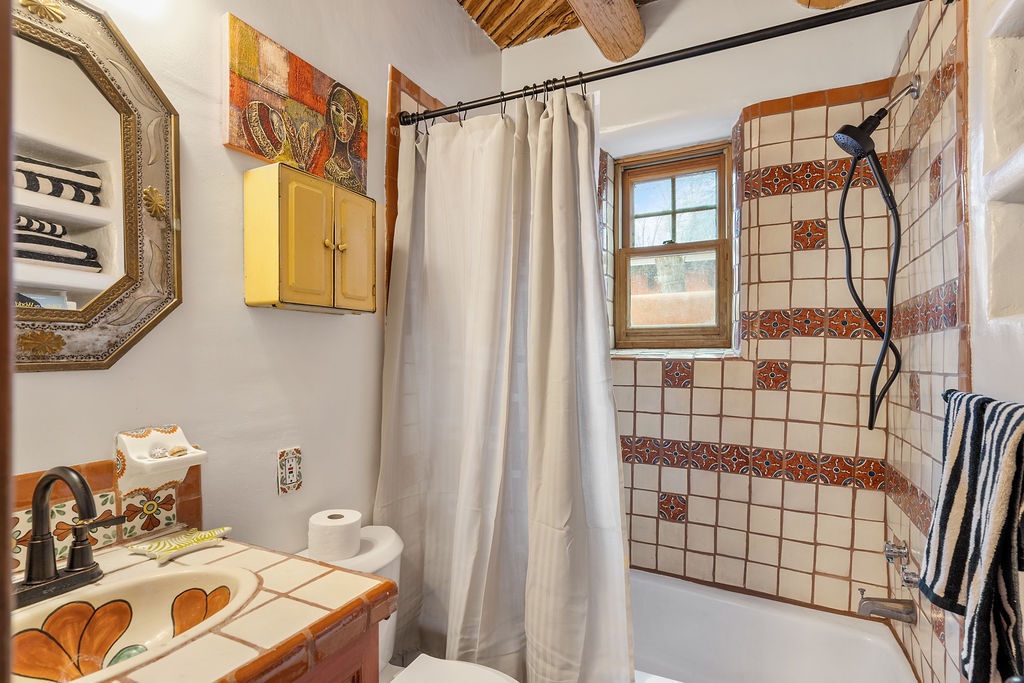 Step into this charming bathroom where colorful Talavera tiles and rustic wooden beams create authentic Mexican warmth for your daily rituals.