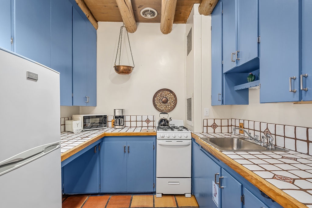 Your charming kitchen features rustic beams, cheerful blue cabinets, and tiled counters - perfect for creating memorable meals during your stay.