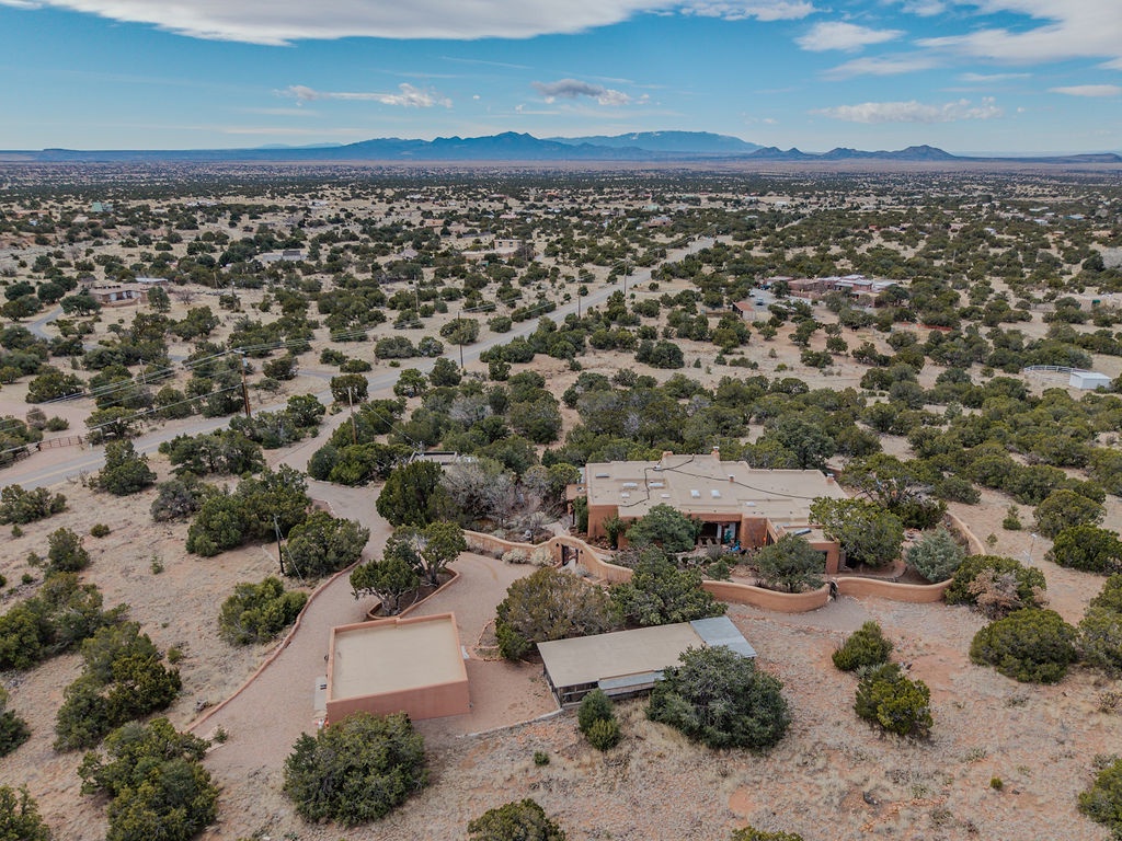 Aerial view of a desert property nestled among native vegetation with mountain ranges visible in the distance.