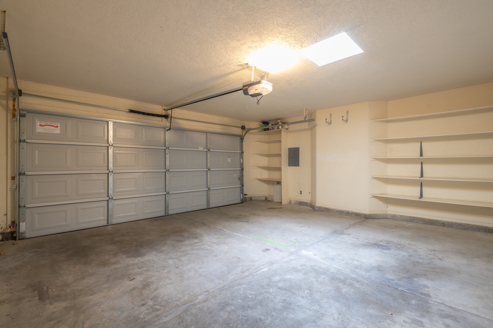 Spacious garage with built-in shelving and secure overhead door for convenient vehicle parking and storage.