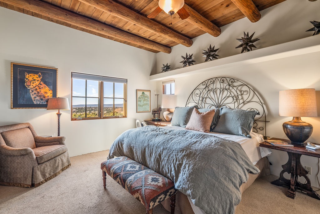 Unwind in your elegant bedroom with exposed beam ceilings, iron headboard, and panoramic windows framing breathtaking valley views.
