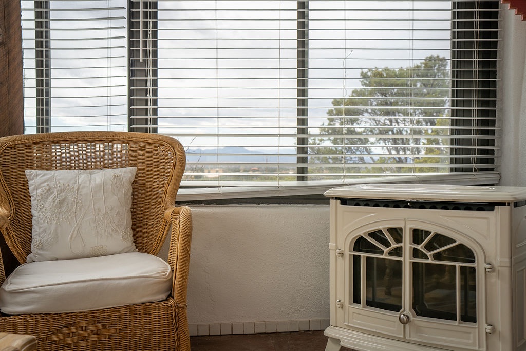 Cozy up in this wicker chair by the fireplace, where warm afternoons blend with peaceful views through bright windows.