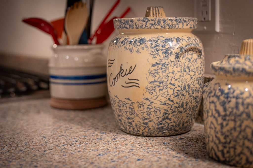 Charming ceramic canisters and colorful cookware grace your counter, making meal prep feel like an art form in this thoughtfully appointed kitchen.