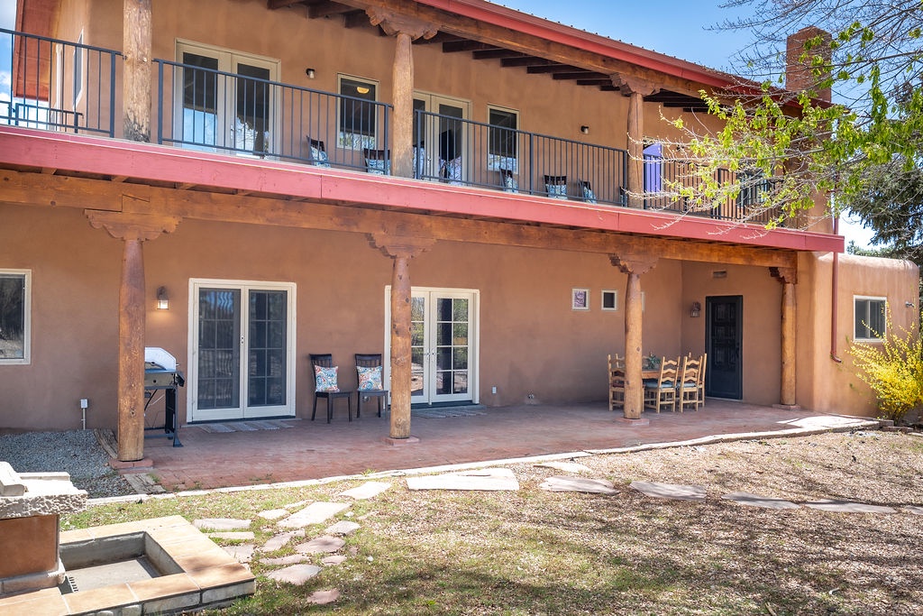 Charming Southwestern adobe-style property featuring rustic wooden columns and spacious covered porches overlooking natural landscaping.