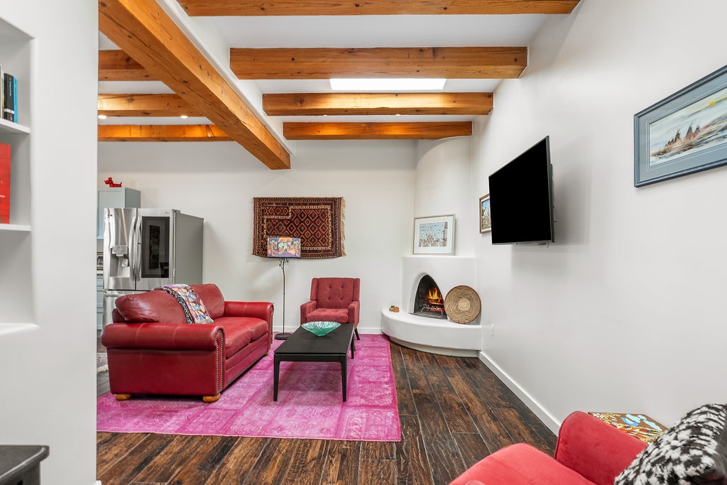 Unwind in this charming living room where rustic exposed beams meet modern comfort. Sink into plush red seating while enjoying your favorite shows.