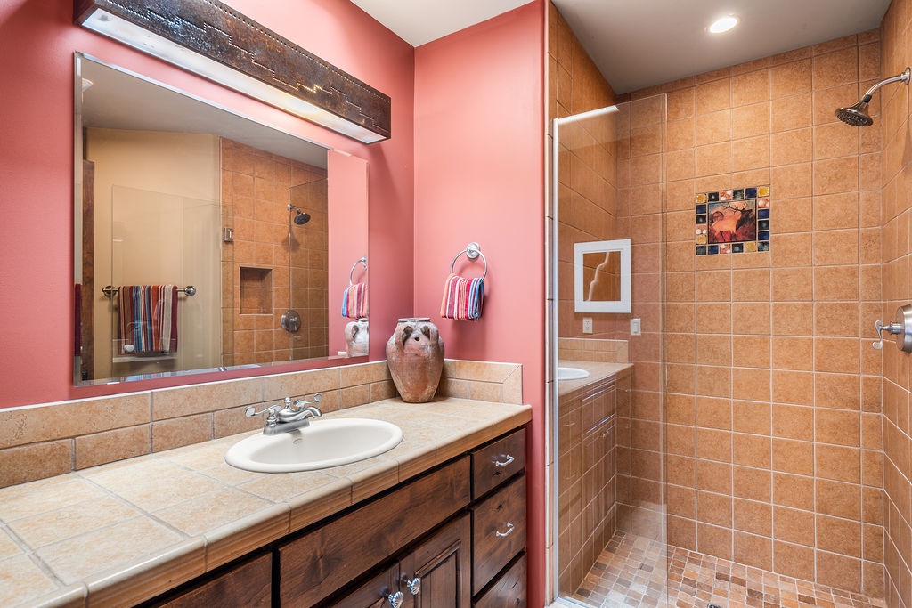 Step into your vibrant bathroom with warm coral walls, spacious walk-in shower, and rustic wood vanity for refreshing mornings.