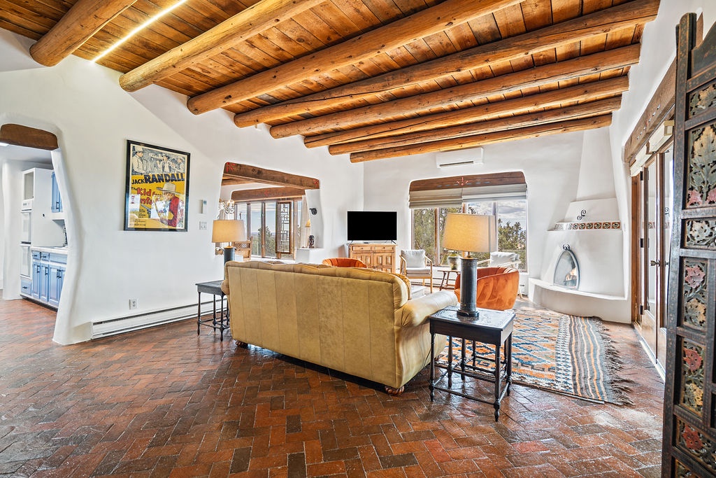 Relax in your spacious living room featuring exposed wood beam ceilings, cozy seating, and charming southwestern architecture that creates the perfect retreat atmosphere.