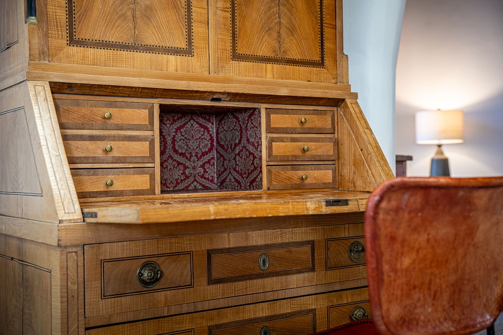 Relax beside this beautiful vintage writing desk, where rich wood craftsmanship and elegant details create your perfect workspace retreat.