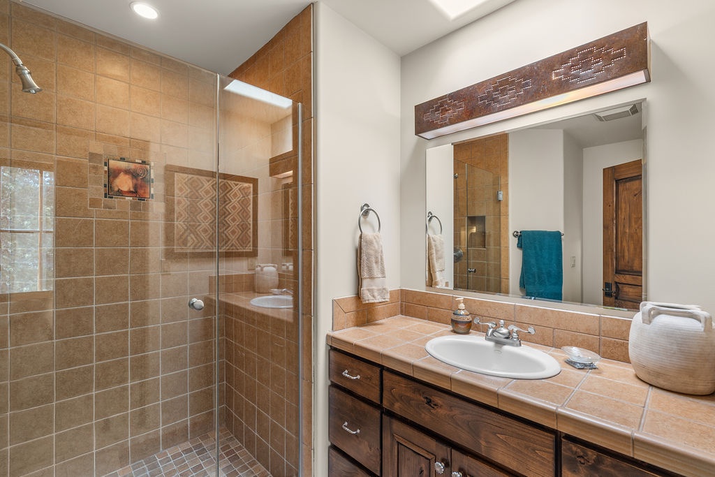 Relax in your spa-inspired bathroom featuring warm tile work, walk-in shower, and thoughtful touches like plush towels.
