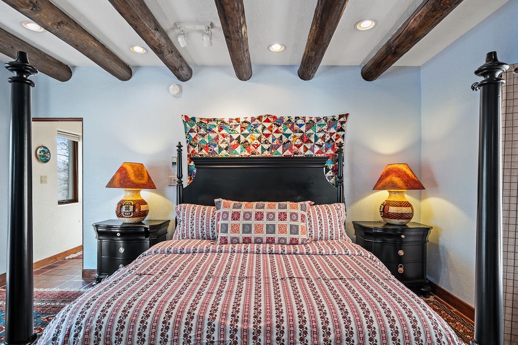 Rest beneath rustic wooden beams in your charming bedroom, where handcrafted textiles and warm lighting create a cozy retreat.