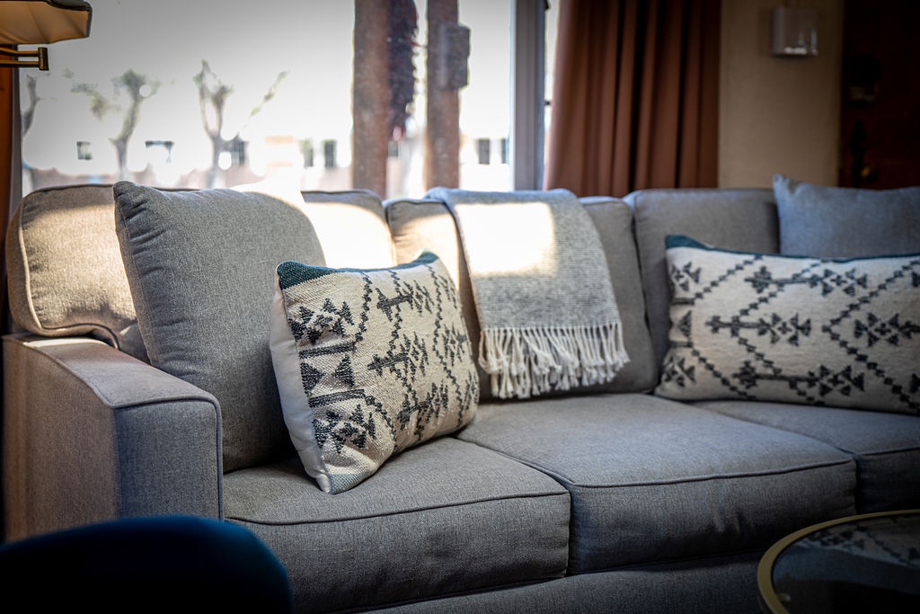 Sink into this plush sectional sofa adorned with bohemian pillows, where natural light streams through your window creating the perfect reading nook.