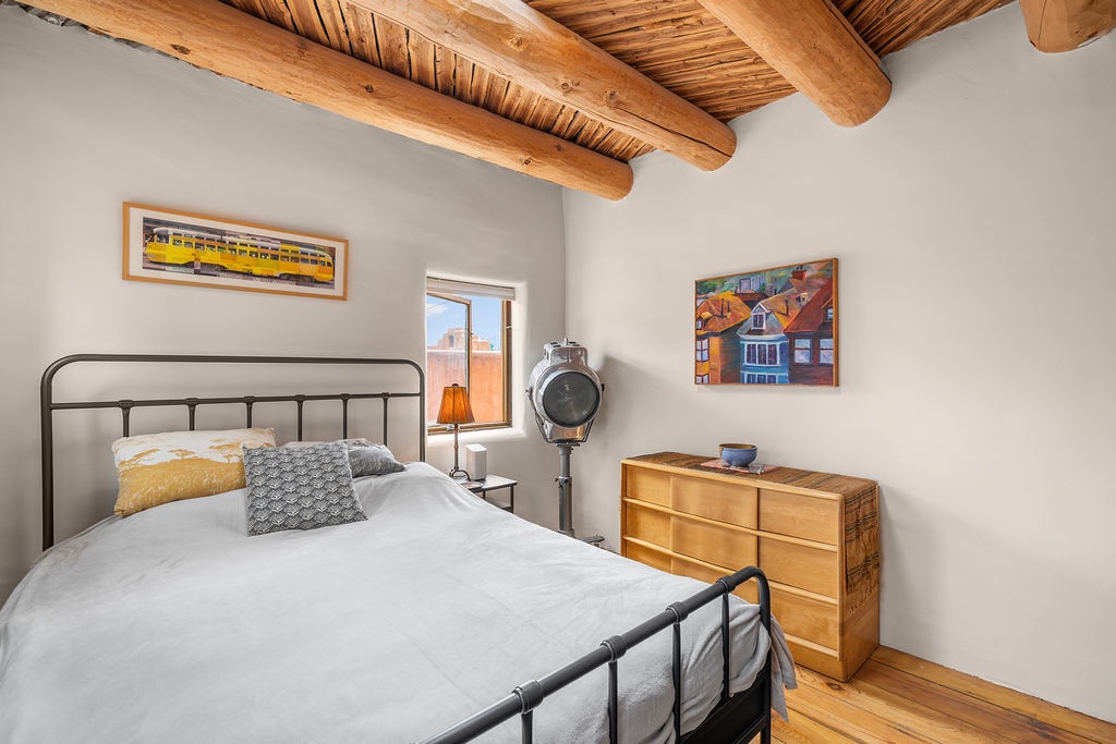 Drift off beneath stunning exposed wooden beams in your cozy bedroom, where artful touches and warm natural light create the perfect retreat.