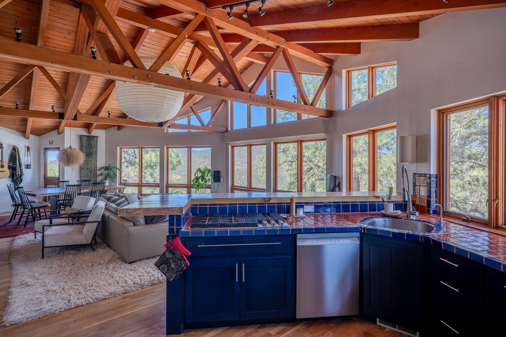 Sunlight floods through floor-to-ceiling windows, illuminating the soaring timber beams and open-concept living space where you'll cook, dine, and relax surrounded by treetop views.