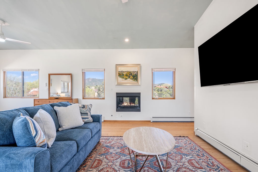 Relax in your bright living room with cozy blue sofa, crackling fireplace, and stunning mountain views through picture windows.