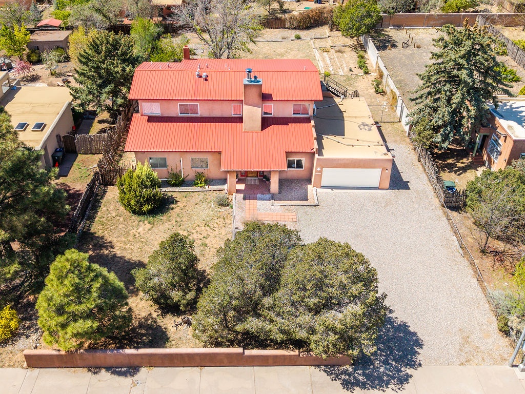 Spacious southwestern-style home with distinctive red roof nestled in a quiet residential neighborhood, featuring ample parking and mature landscaping.