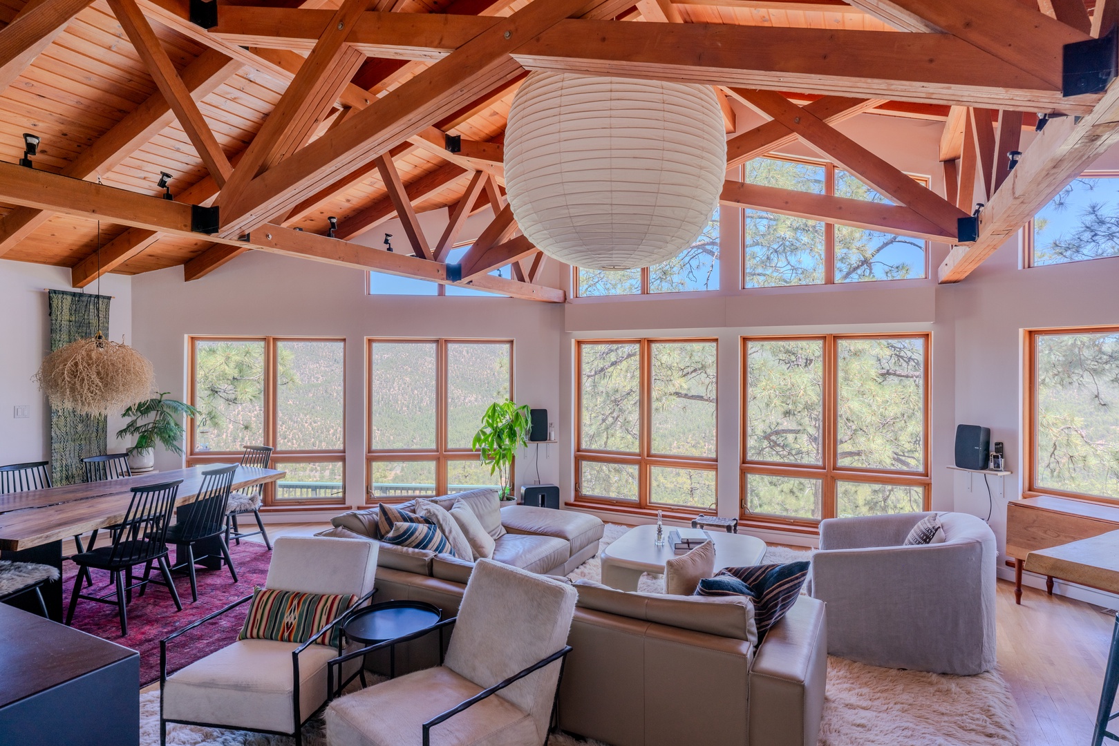 Soaring timber-frame ceilings and floor-to-ceiling windows fill your living space with natural light and sweeping forest views, creating an open and airy retreat.