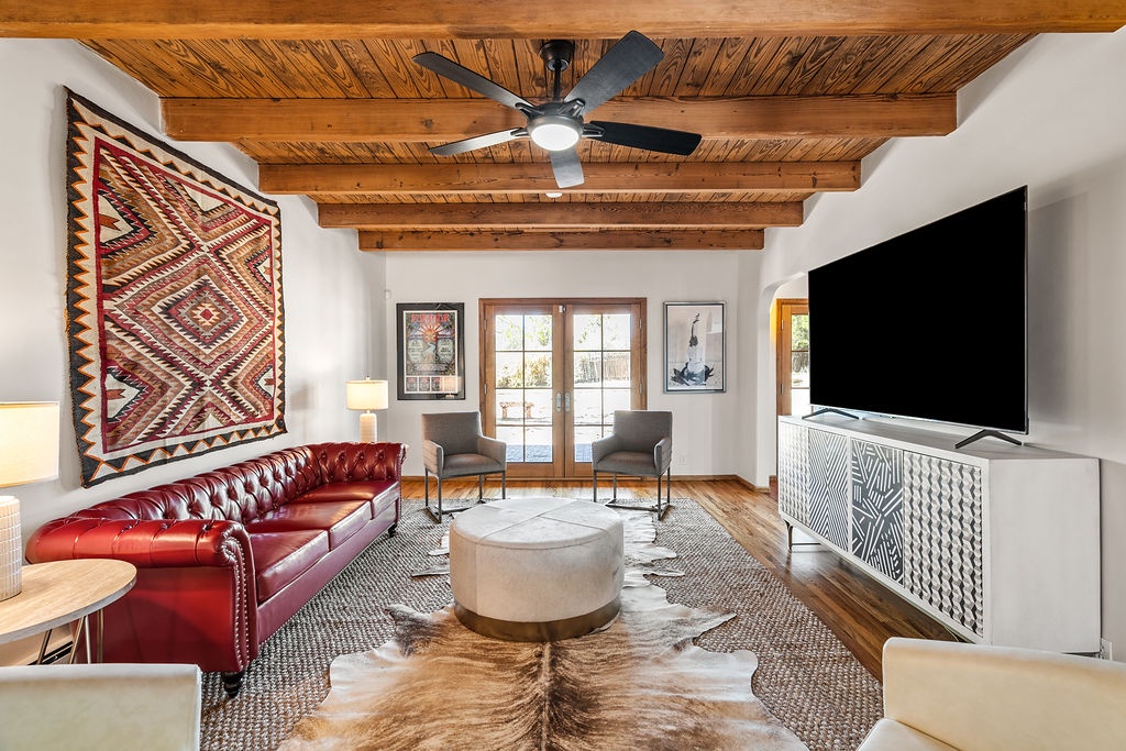 Relax in your stylish living room with exposed wood beams, plush leather seating, and modern entertainment center perfect for unwinding after exploring.