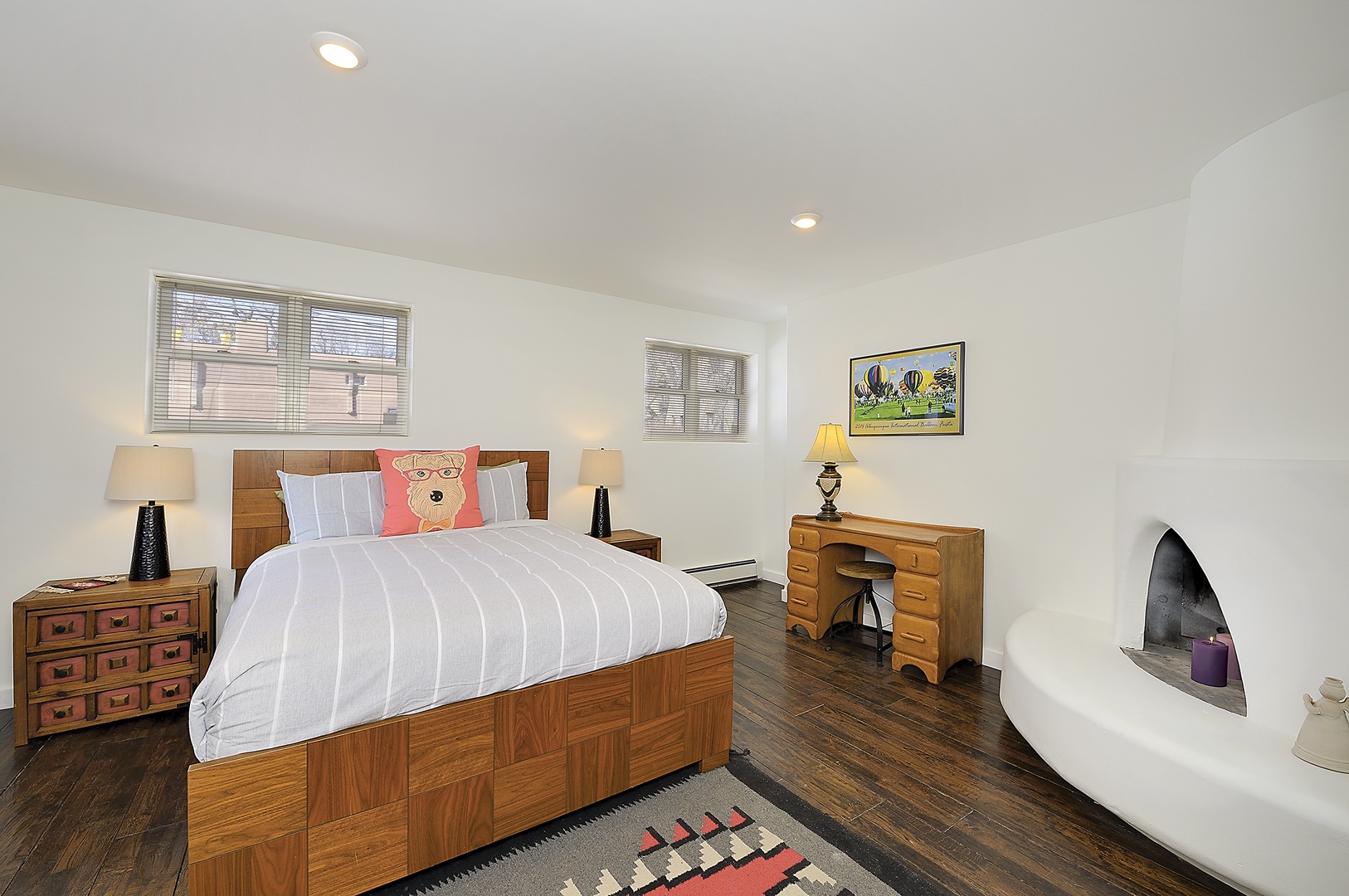 Relax in your cozy bedroom featuring warm wood furnishings, crisp linens, and a charming fireplace for intimate evenings.