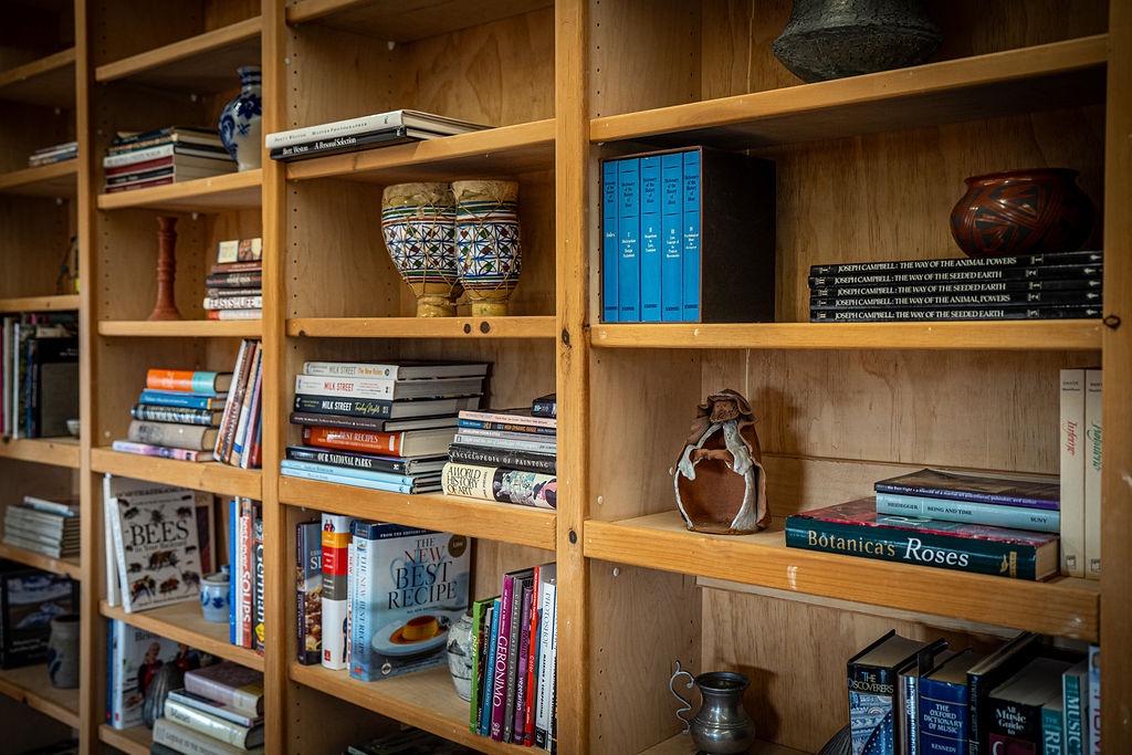 Curl up with a good book from this thoughtfully curated library, featuring cozy reading nooks and charming pottery accents for quiet moments.