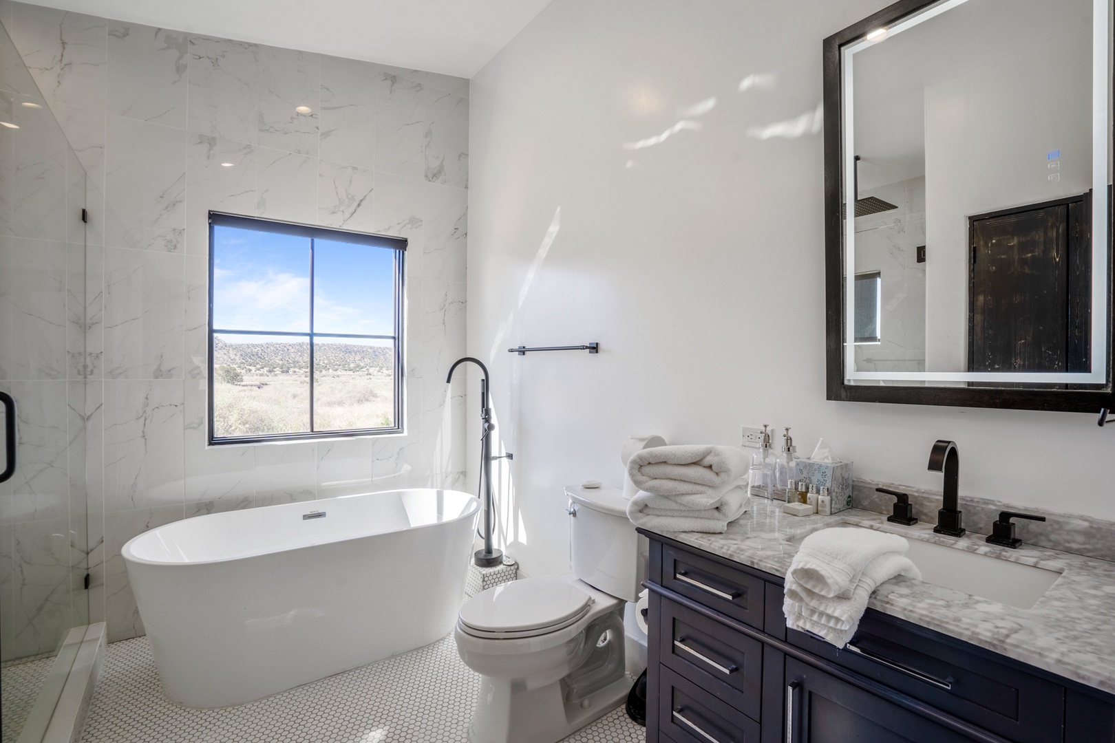 Unwind in your luxurious marble bathroom with soaking tub and stunning landscape views through the oversized window.