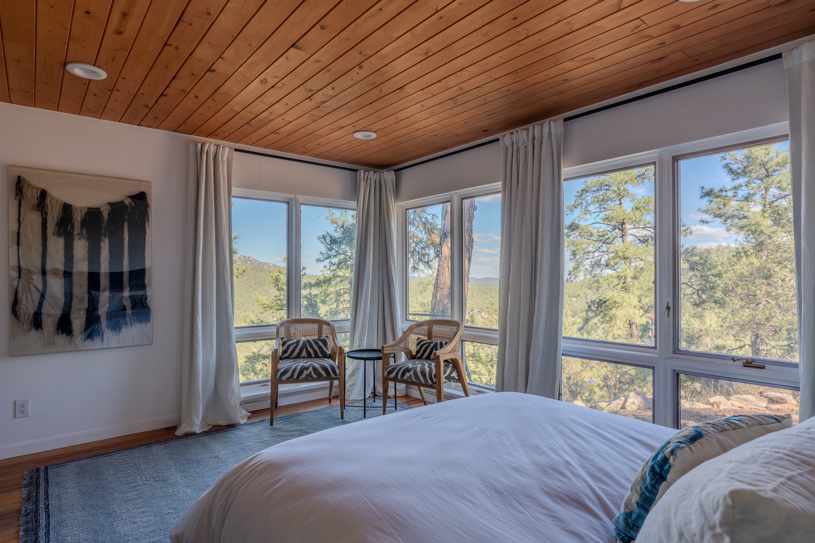 Wake up to mountain and forest views from your cozy bedroom, where warm wood ceilings and a private seating nook create a peaceful retreat.