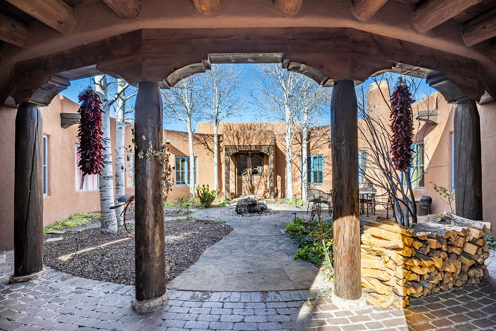 Traditional Southwest adobe architecture frames this charming property entrance with exposed wood beams and rustic courtyard design.