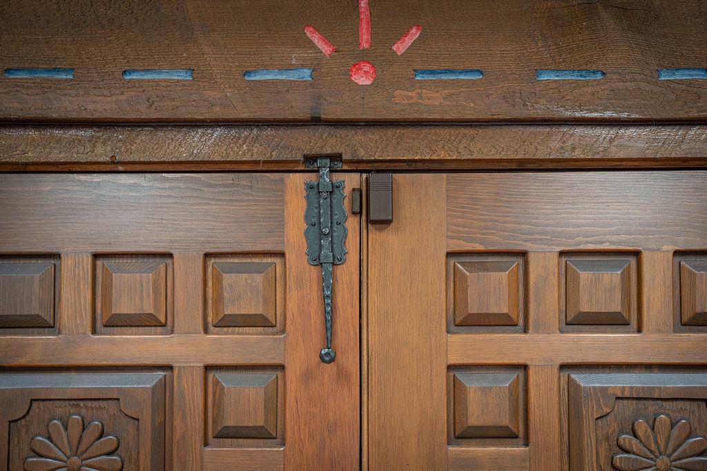 Step through this beautiful handcrafted wooden entrance featuring traditional ironwork and charming decorative details that welcome you home.