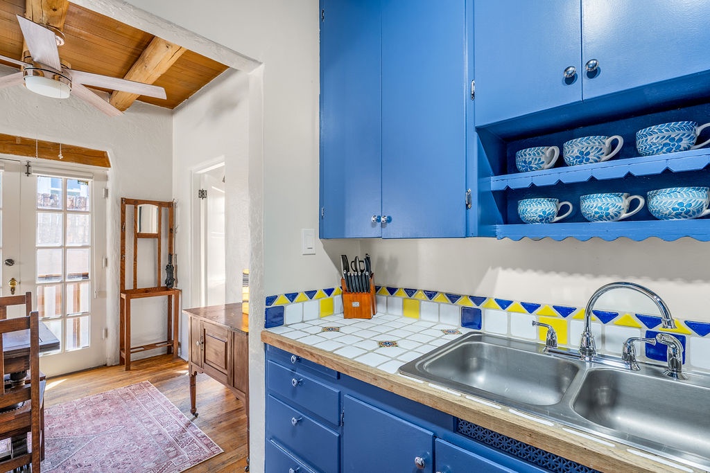 Your charming blue kitchen features colorful tile backsplash and cheerful dishes ready for memorable meal preparations.