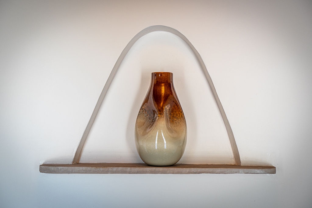 Admire this elegant amber glass vase nestled in your room's charming architectural niche, adding warmth to your peaceful retreat.