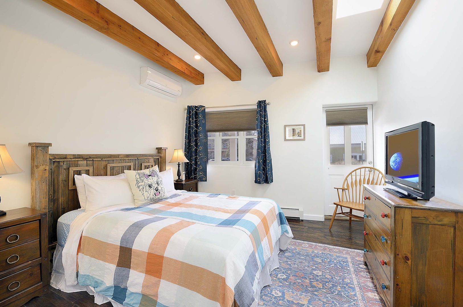 Unwind in your cozy bedroom featuring exposed wooden beams, charming rustic furniture, and modern amenities for your comfort.