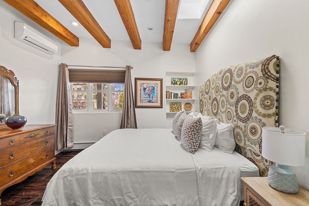 Drift off under stunning wooden beams in your peaceful retreat, where artistic touches and cozy linens create the perfect sanctuary.