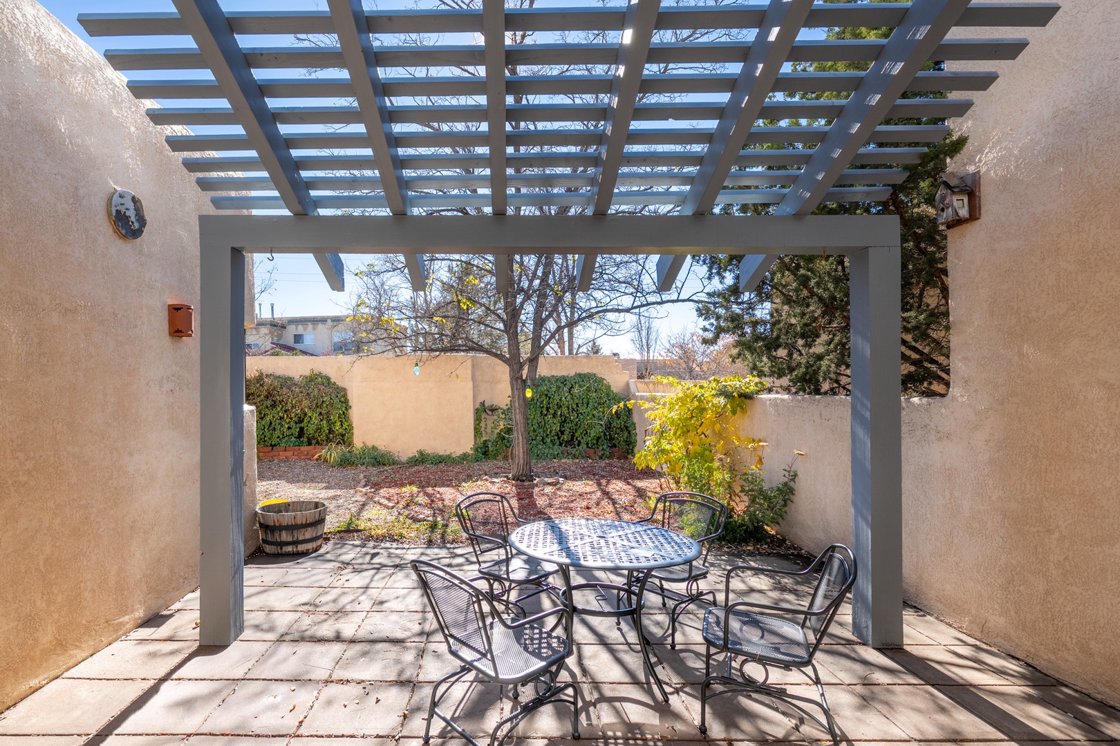 Relax at your private outdoor dining table under the pergola, where dappled sunlight creates a perfect ambiance for meals and morning coffee in your enclosed patio space.